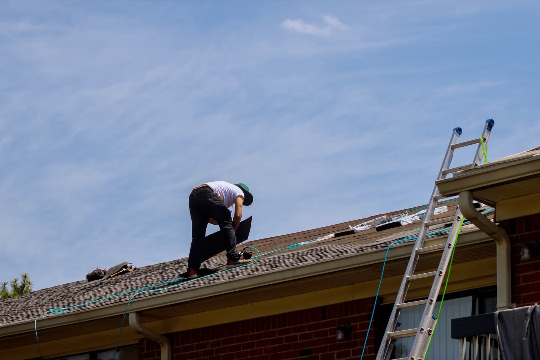 Roofer repairing asphalt shingles on a residential roof